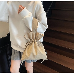 Dettaglio della borsa a secchiello plissettata beige con coulisse ed etichetta nera