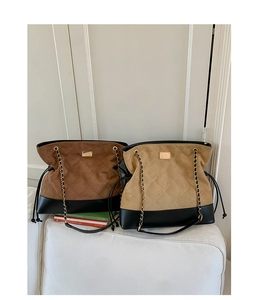 Detail of quilted tote bags in caramel and beige with metal chain straps and drawstring