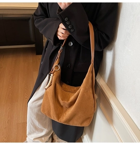 Detail of tan suede hobo bag featuring decorative wooden beads and smooth leather strap