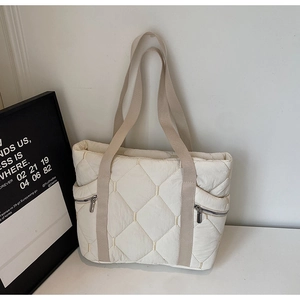 Detail of quilted tote bag with side zipper pockets and khaki wide shoulder strap