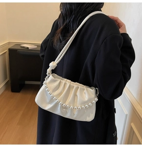 Detail of white pleated handbag with pearl chain strap and glossy leather finish
