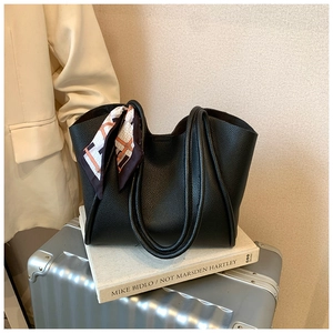 Dettaglio borsa tote in pelle martellata nera con sciarpa di seta e manici sottili