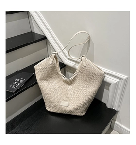 Detail of cream woven tote bag with textured hobo design on modern staircase