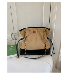 Detail view of khaki quilted suede and black leather stitching with gold chain strap