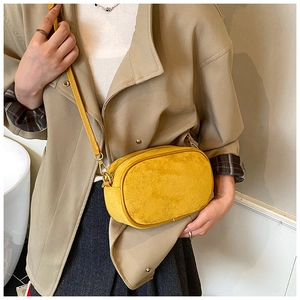 Detail of matte yellow crossbody bag with gold hardware and slim leather strap