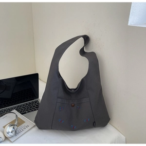 Detail der dunkelgrauen Canvas-Tasche mit TELN-Stickerei und Tasche mit Druckknopfverschluss