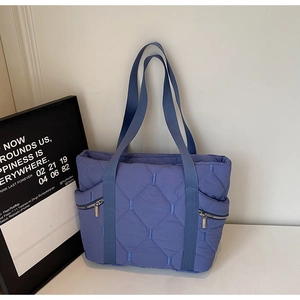 Detailed macro view of blue quilted tote bag fabric with rhombus patterns and side zippers