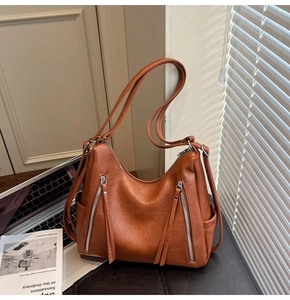 Close-up of caramel tote bag featuring long tassel zippers and natural leather texture