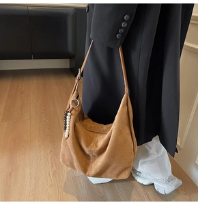 Close-up of brown suede hobo bag with delicate bead charm detail and slim strap