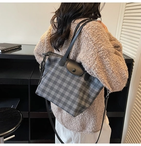 Close-up of checkerboard tote bag with leather flap and snap closure held by model