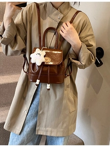 Brown vintage leather backpack with adjustable straps and a cute white teddy bear charm