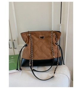 Detail of quilted brown suede and black leather bucket bag with golden chain strap