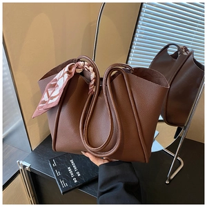 Dettaglio della borsa tote in pelle marrone scuro con elegante foulard in seta sul manico