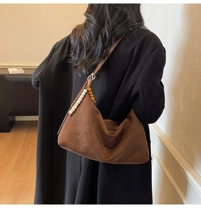 Détail du sac hobo en daim marron foncé avec pendentif en perles de bois et fermeture éclair