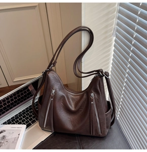 Detail of dark brown vintage faux leather tote with tassel zippers and side pockets