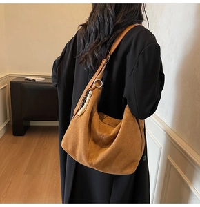 Detail of vintage brown suede hobo bag featuring ethnic wooden bead pendant and large capacity