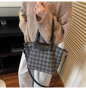 Detail of checkered tote bag showing leather handles, metal snap button and long shoulder strap