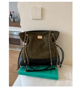 Detail of olive green suede tote with diamond quilting and gold chain strap