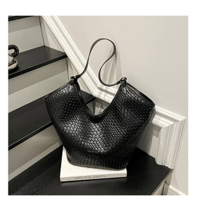 Close-up of black woven leather tote bag texture on minimalist steps with artistic book