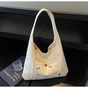 Detail der weißen Canvas-Tasche mit TELN-Stickerei und Vintage-Knopfverschluss am Taschenrand