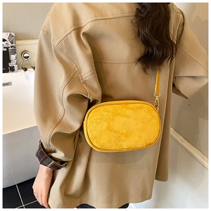 Crossbody matte yellow bag detail showing suede texture and golden metal hook on model