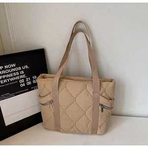 Detail of khaki quilted tote bag with hexagonal pattern and side zipper pockets