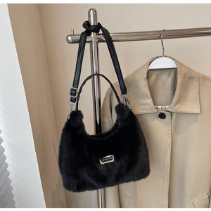 Détail du sac croissant en fausse fourrure noire avec plaque logo en métal argenté