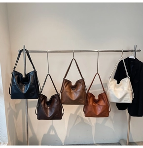 Selection of large vintage tote bags in five earthy tones displayed on a metal rack