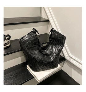Detailed view of black woven texture on bucket tote bag with sleek shoulder strap