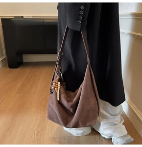 Detail view of dark brown suede hobo bag with ethnic bead tassel on female model