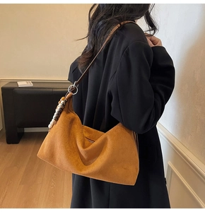Détail du sac hobo en daim marron avec pendentif en perles et bandoulière élégante