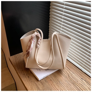 Dettaglio della borsa tote in pelle martellata bianco crema con sciarpa di seta su scale