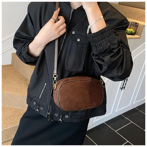Detailed close-up of brown suede crossbody bag with gold hardware and vintage texture