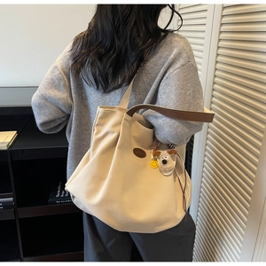 Detail of canvas tote bag with brown leather handles and cute plush dog charm