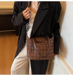Detail of coffee checkered tote bag featuring a leather flap and adjustable shoulder strap