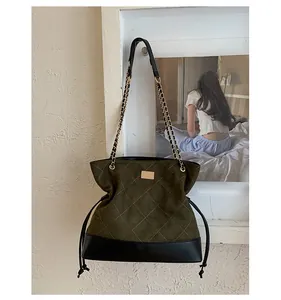Detail of dark green quilted tote bag with golden metal plaque and chain strap
