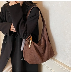 Detail of suede hobo bag with vintage wooden bead charms and smooth matte texture
