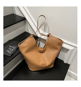 Close-up of brown woven texture and brand logo on minimalist PU leather bucket tote bag