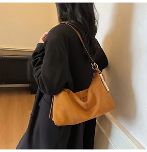 Détail d'un sac hobo en daim marron avec anneau argenté et pendentif en perles
