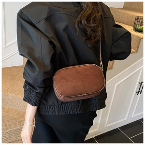 Detail of dark brown faux suede crossbody bag with gold hardware worn by model