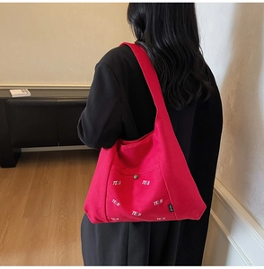 Detailaufnahme der roten Canvas-Tasche mit bunter TELN-Stickerei und Metall-Druckknopf