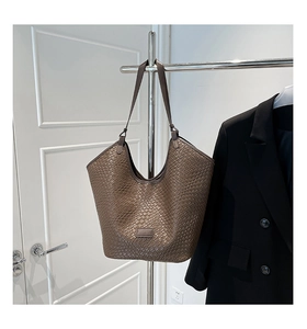 Detailed view of the brown woven leather texture and logo on this stylish tote bag