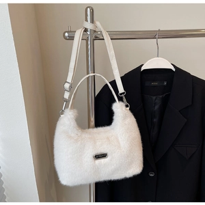 Détail du sac à bandoulière en peluche blanche avec sangle en cuir et plaque logo métal
