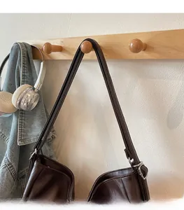 Detail of soft brown leather shoulder straps with silver metal rings on a vintage tote bag