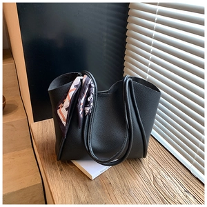 Dettaglio della borsa tote nera in pelle martellata con elegante foulard in seta decorato