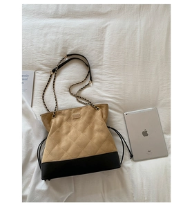 Flat lay of quilted tote bag with gold chain strap next to a tablet and magazine
