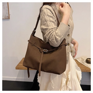 Macro detail of dark brown faux suede tote bag featuring silver buckle and matte texture