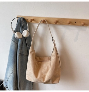 Detail of suede hobo bag with contrast strap and metal buckle on wall hook
