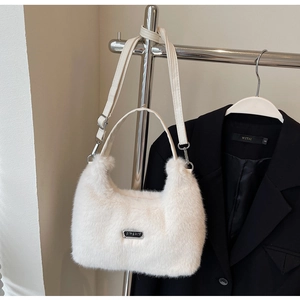 Détail d'un sac bandoulière blanc en fausse fourrure avec poignée ronde et logo métal
