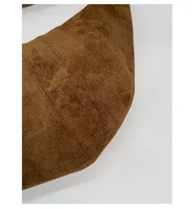 Detailed close-up of brown suede hobo bag featuring vertical stitching and matte texture